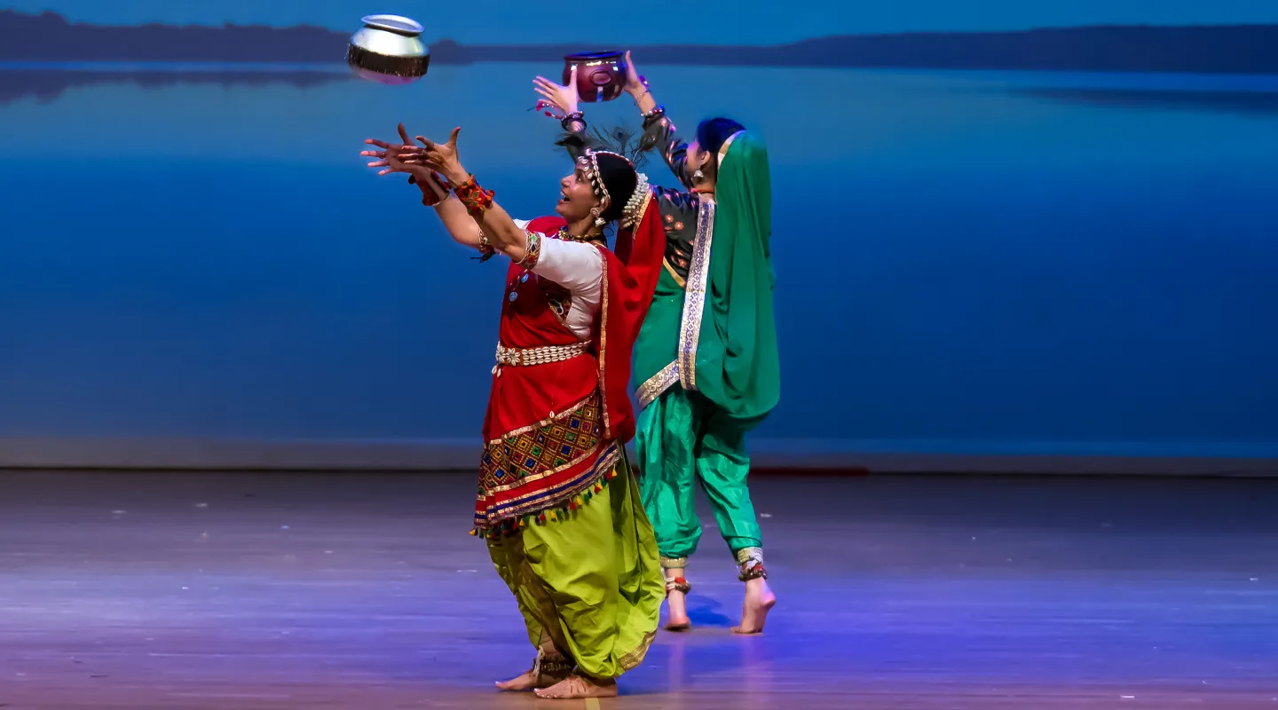 Two dancers throwing water containers into the air