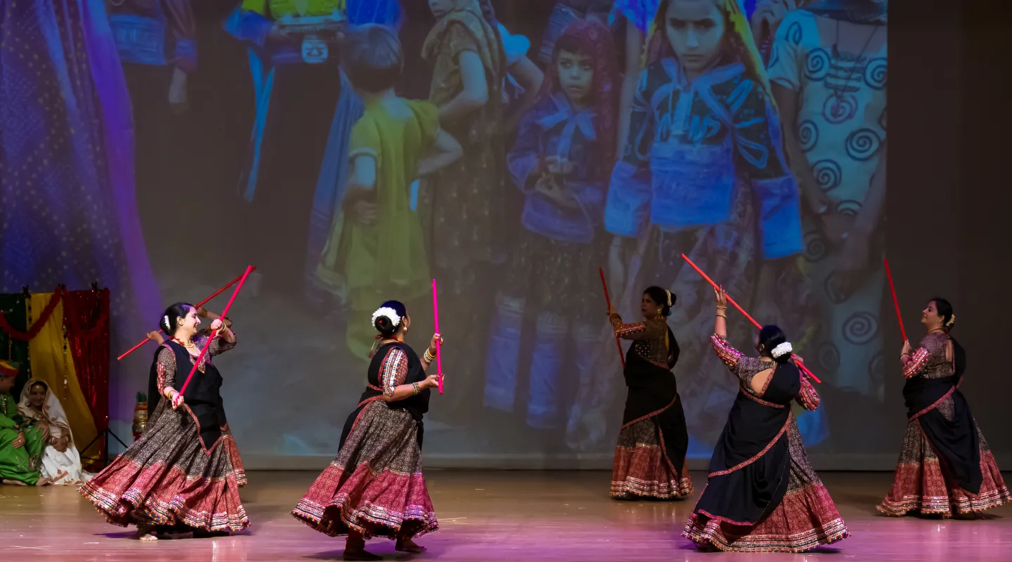 A student striking decorative sticks on stage