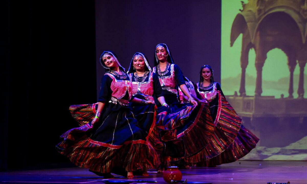 Students in formation on stage during Kalbelia performance.